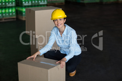 Portrait of female factory worker picking up cardboard boxes