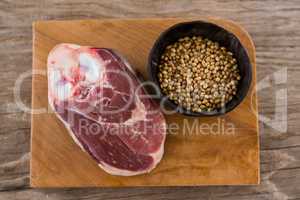 Sirloin chop and coriander seeds on wooden tray