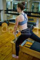 Determined woman performing stretching exercise on reformer