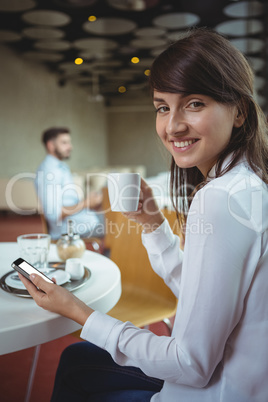 Executive using mobile phone while having coffee in cafÃ?Â©