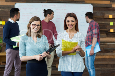 Smiling businesspeople standing with file in office