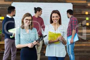 Smiling businesspeople standing with file in office