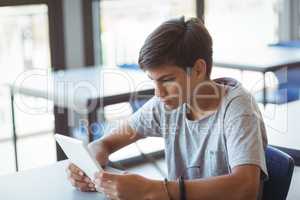 Attentive schoolboy using digital tablet in classroom