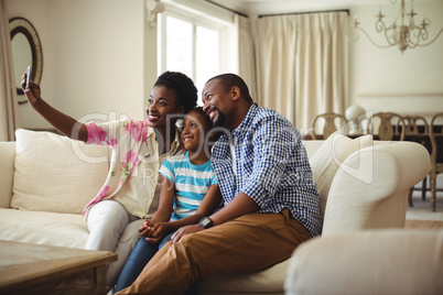 Family taking selfie on mobile phone in living room