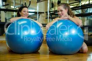 Portrait of happy women leaning on fitness ball