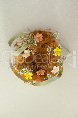 Nest decorated with flowers against white background