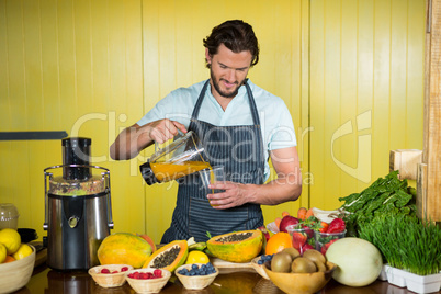 Male staff pouring juice into glass at counter