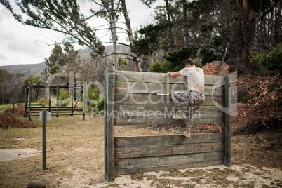 Soldier climbing wooden wall in boot camp