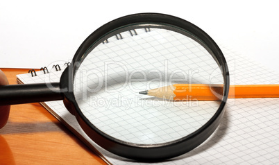 Pencil and magnifier on a notebook