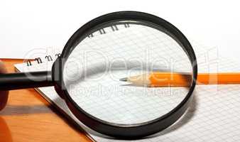 Pencil and magnifier on a notebook