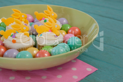 Colorful chocolates and cupcakes in bowl