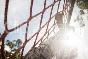 Military soldier climbing rope during obstacle course