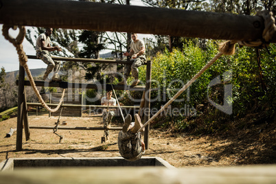 Young military soldiers practising rope climbing during obstacle course