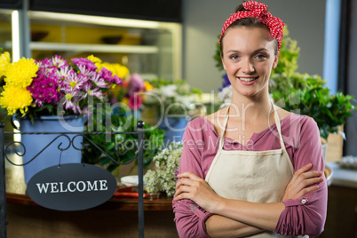 Happy female florist standing with arms crossed in flower shop