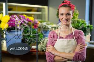 Happy female florist standing with arms crossed in flower shop