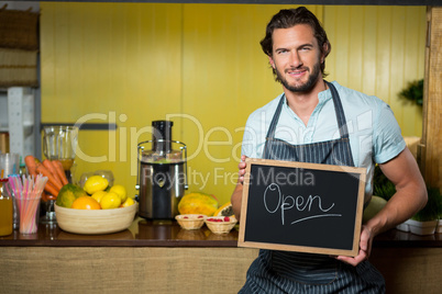 Smiling shop assistant holding a board with open sign