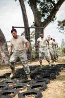 Young military soldiers practicing tyre obstacle course