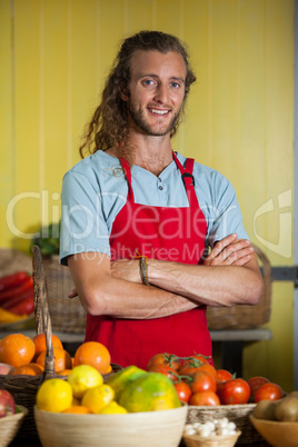 Smiling male staff standing with arms crossed in organic section