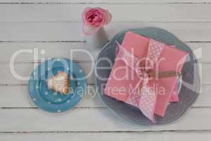 Gift box, flower vase and cookie on wooden surface
