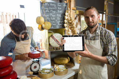 Portrait of staff showing digital tablet at counter