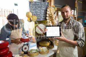 Portrait of staff showing digital tablet at counter