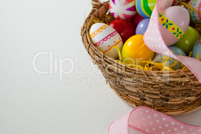 Various Easter eggs with ribbon in wicker basket