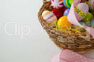 Various Easter eggs with ribbon in wicker basket