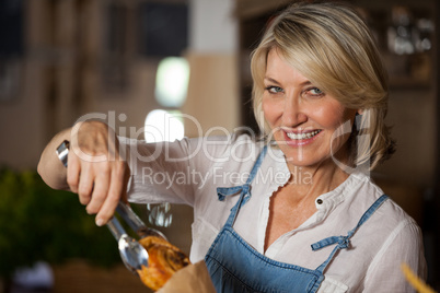 Female staff packing sweet food in paper bag