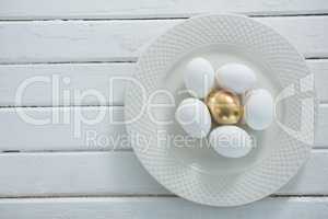 Golden Easter egg with white eggs in plate