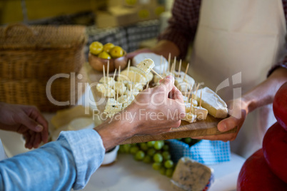 Staff showing a sample of cheese to customer at counter