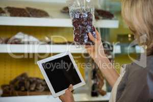 Female staff maintain records of meat on digital tablet at counter