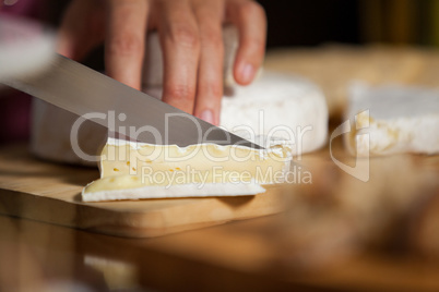 Female staff cutting cheese at counter in market