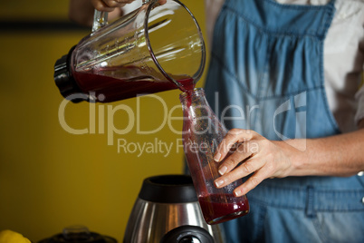 Mid-section of female staff preparing a juice