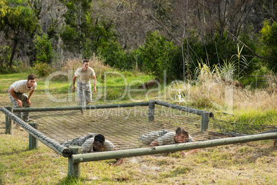 Soldiers crawling under the net during obstacle course