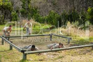Soldiers crawling under the net during obstacle course