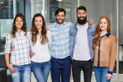 Portrait of male and female executives standing arms around