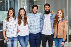 Portrait of male and female executives standing arms around