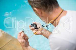 Swim coach looking at stop watch near poolside