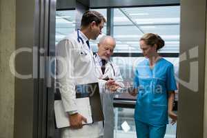 Doctors and surgeon using digital tablet in elevator