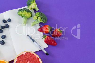 Measuring tape, various fruits, vegetable, opened book and pen