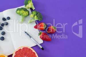 Measuring tape, various fruits, vegetable, opened book and pen