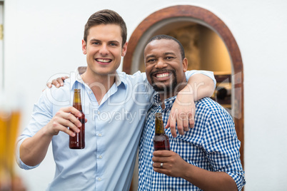 Friends hugging each other while holding beer bottles