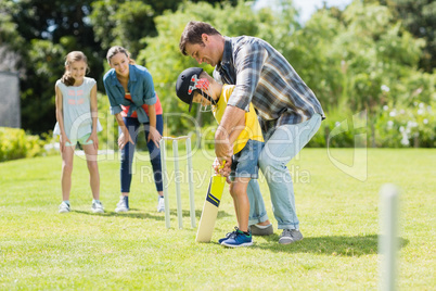 Happy family playing cricket together