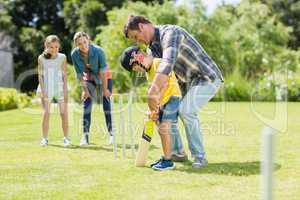 Happy family playing cricket together