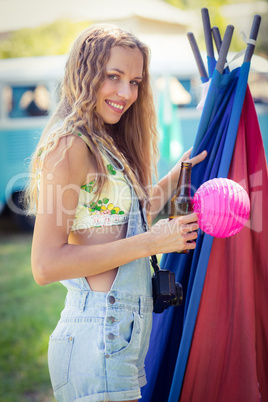 Portrait of woman holding beer bottle at campsite