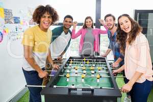 Happy graphic designers playing table football