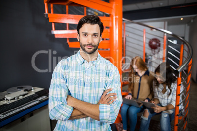 Male executive standing with arms crossed in office