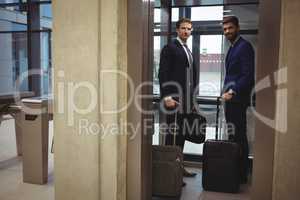 Portrait of businessmen standing with luggage