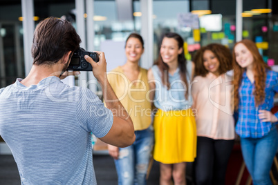 Man photographing his female colleagues with camera Man photographing his female colleagues with camera