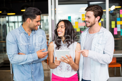 Three smiling executives discussing over digital tablet